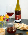 Bottle of Good Measure 2023 Oregon Grenache with burgundy and blue label next to glass and food